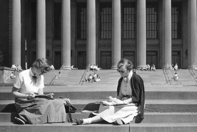 black and white image of two female student studying on steps in front of Northrop, appearing to be from the 1940s