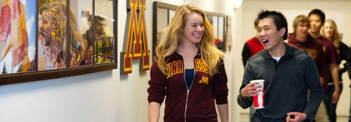 students walking in hall with U of M logo visible on wall