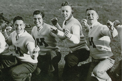 Male students wearing M sweaters and posing on field