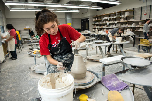 Student working on clay wheel in ceramics class